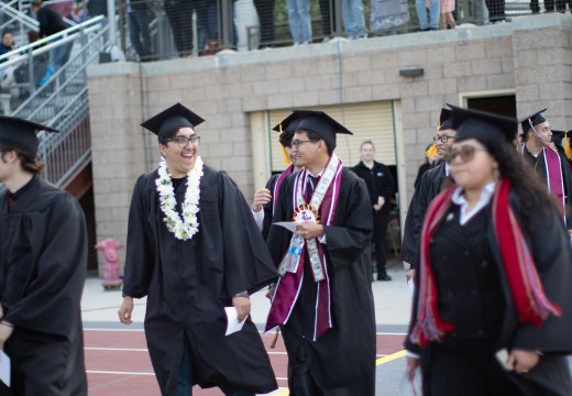 Group of graduates smile as they walk during Commencement. 