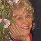 Barbara Hogan smiling next to flowers.