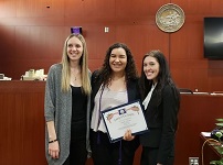 three students posing with graduation certificates