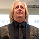 Mark Pursley lecturing in a faded gold brocade suit jacket with black tie.
