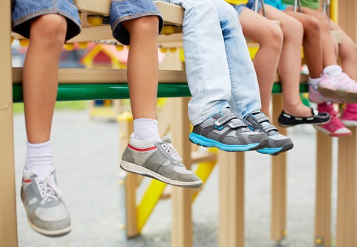 Kids sitting on playground equipment with feet hanging down