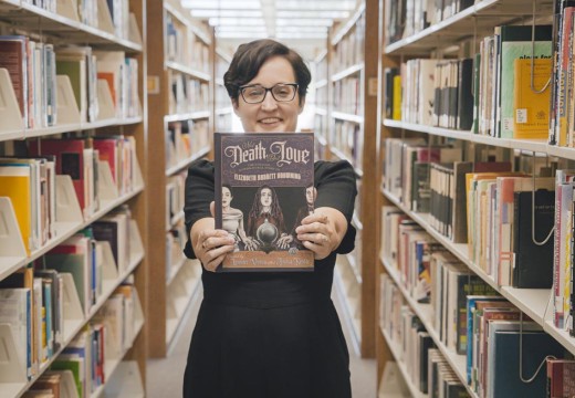 Former AVC student Lavender Vroman holding book titled: Not Death, But Love: The Strange, Supernatural Story of Elizabeth Barrett Browning.