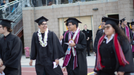 Group of graduates smile as they walk during Commencement. 