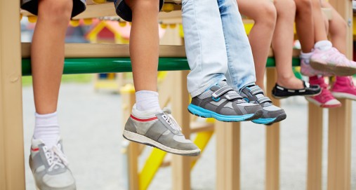 Kids sitting on playground equipment with feet hanging down